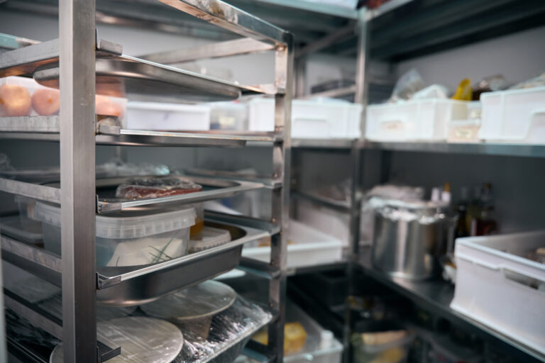 Focus on foreground of dishes on shelves in blurred refrigerator storage in restaurant. Concept of tasty healthy eating